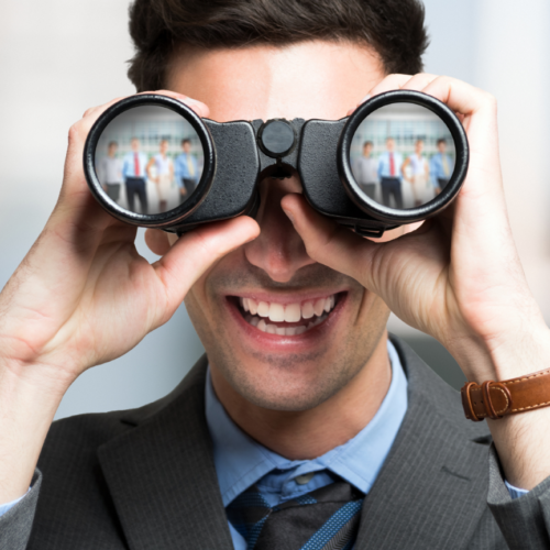 Junger Mann sucht mit Fernglas nach Personal.