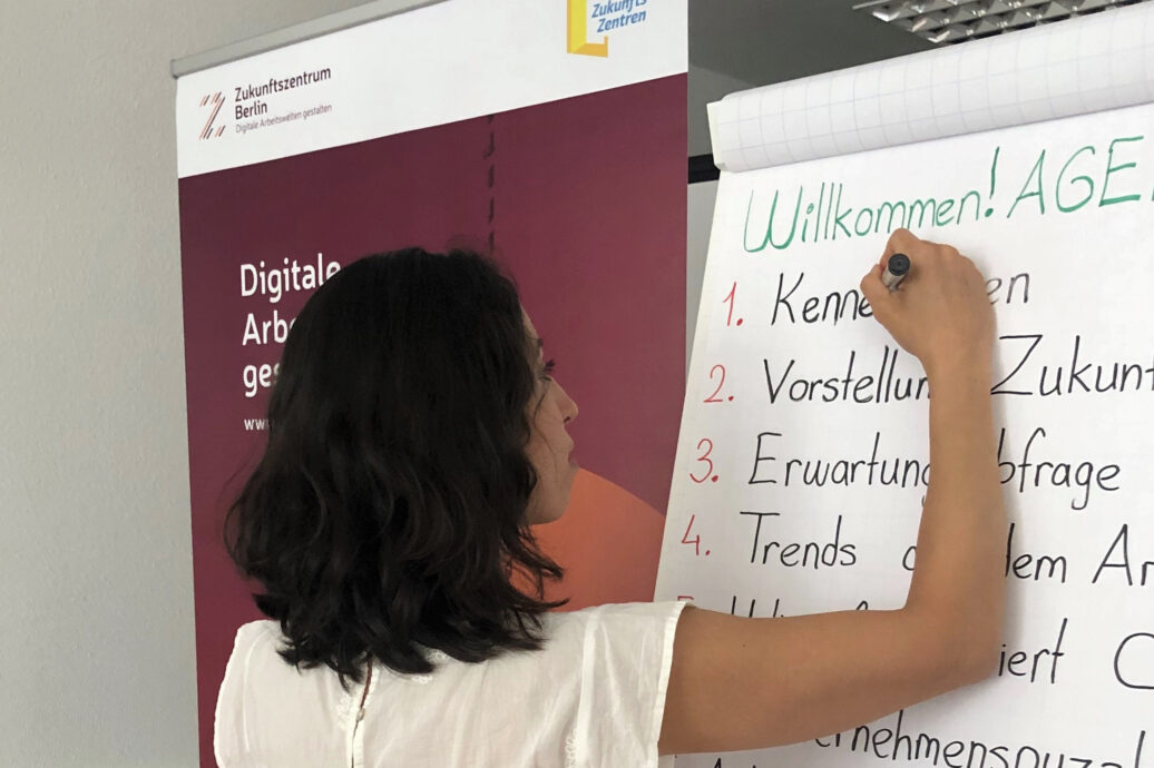 Eine Frau schreibt an ein Flipchart.