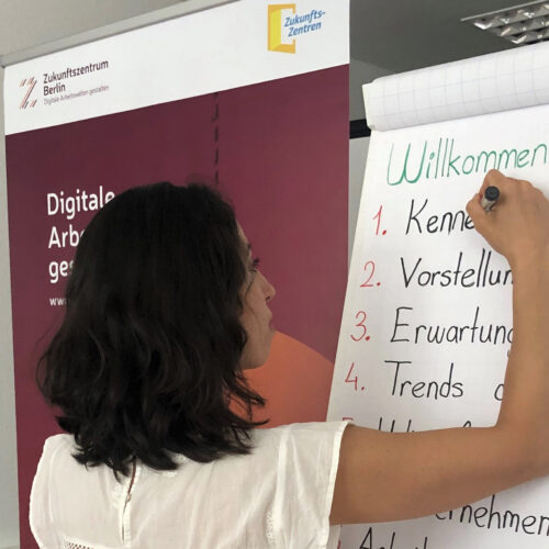 Eine Frau schreibt an ein Flipchart.
