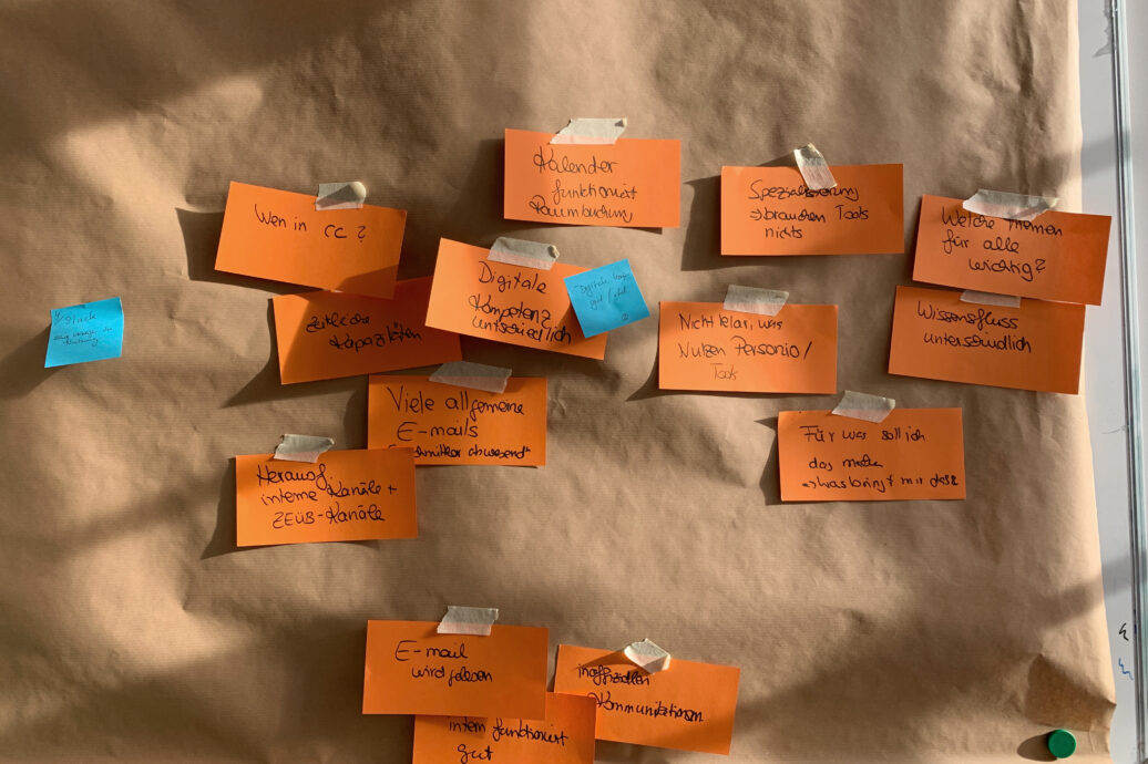 Handbeschriftete orange Moderationskarten auf Packpapier – Ergebnis einer Workshop-Sammlung zu digitaler Zusammenarbeit.